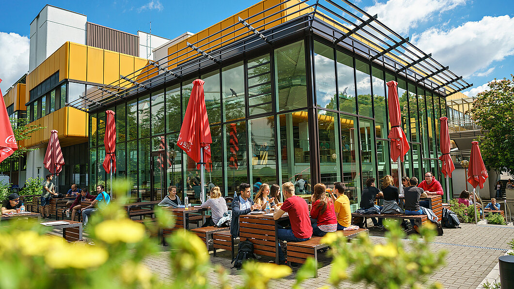 Studierende sitzen im Gartenbereich der Galerie.