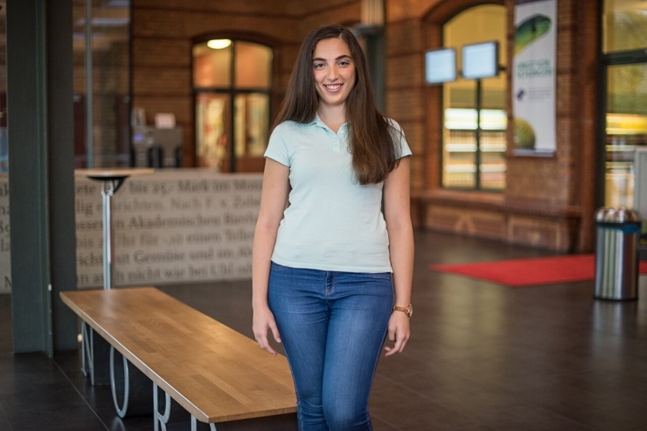 Praktikantin steht im Foyer eines Studentenwerks.