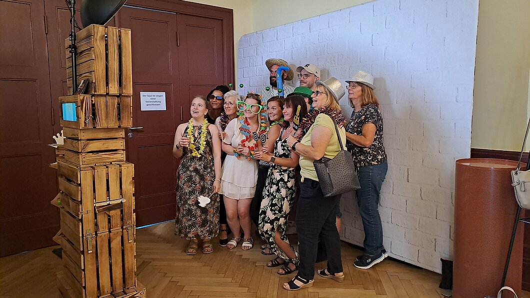 Frauen und Männer in bunten Kostümen vor einer Fotobox
