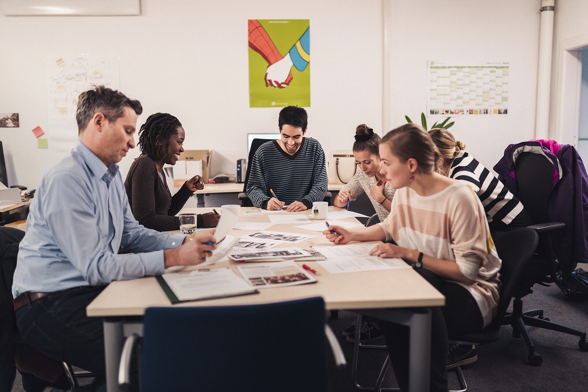 Menschen sitzen zusammen am Bürotisch und tauschen sich aus.