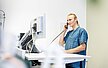 Mitarbeitender steht an seinem Stehtisch und telefoniert