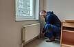 Hausmeister repariert Heizung in einem WG Zimmer