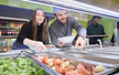 Zwei Studierende beugen sich über die Salatbar in der Mensa CAMPO und bedienen sich.