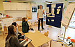 Bild von einer Team-Fortbildung, Mitarbeitende sitzen und eine Person steht am Pinbord