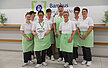 Foto vom Team der Mensa Bambus vor dem Logo der Mensa mit der PETA Urkunde